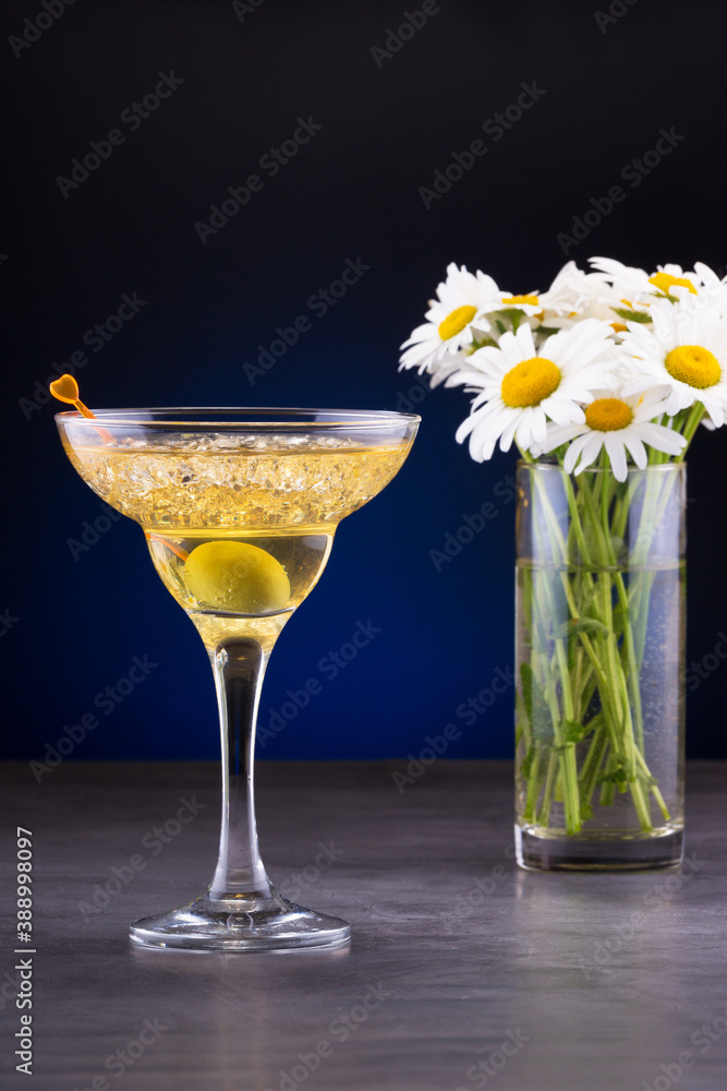 evening martini cocktail with olive and a bouquet of daisy flowers