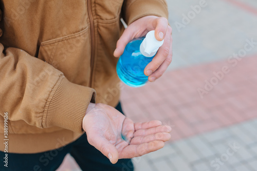 A man disinfects his hands in the parking lot against the background of paving slabs.