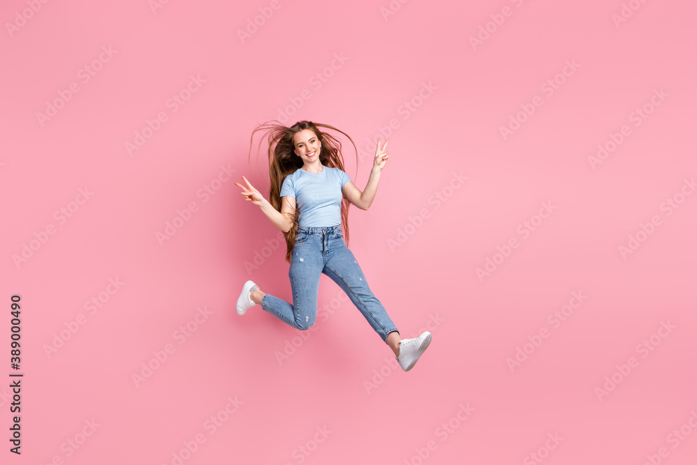 Photo portrait of girl showing two v-signs jumping up isolated on pastel pink colored background