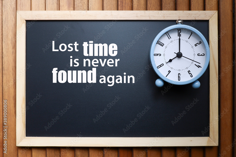 Time concept. Alarm clock on a black chalkboard with a message on time Time concept. Alarm clock on a black chalkboard with a message on time