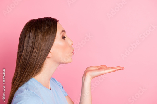 Photo portrait profile of girl blowing air kiss with one hand up isolated on pastel pink colored background