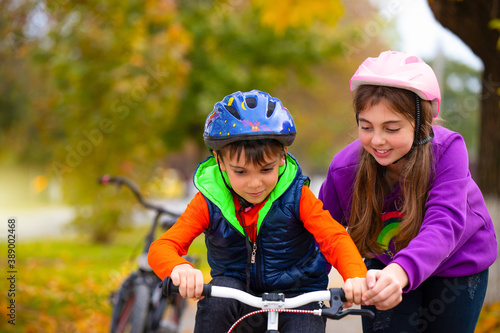 Striving for success. A sister teaches her little brother to ride a bike in the park. Autumn. Family and healthy lifestyle