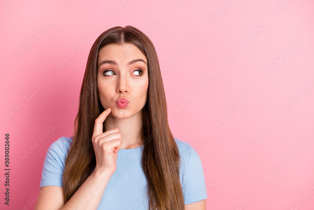 Photo portrait of girl with plump lips touching face chin with finger looking at blank space isolated on pastel pink colored background Photo portrait of girl with plump lips touching face chin with finger looking at blank space isolated on pastel pink colored background