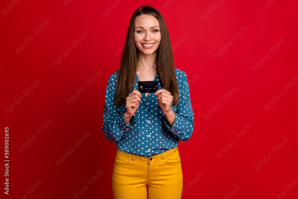 Naklejka premium Portrait of attractive cheerful cheery girl holding in hands bank card isolated over bright red color background