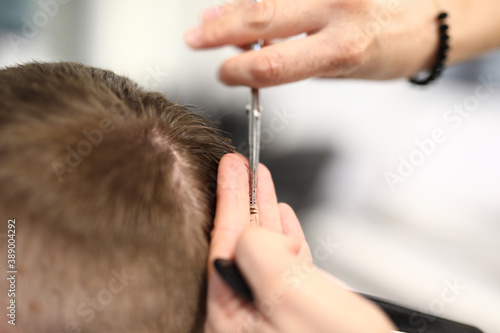 Hands of hairdresser with scissors make short haircut to man in beauty salon closeup. Training for men's haircuts concept.