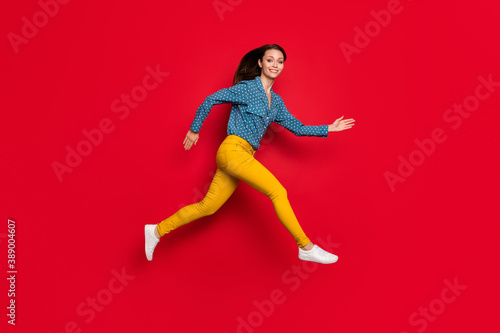Full length body size profile side view of pretty cheerful thin motivated girl jumping running isolated on bright red color background