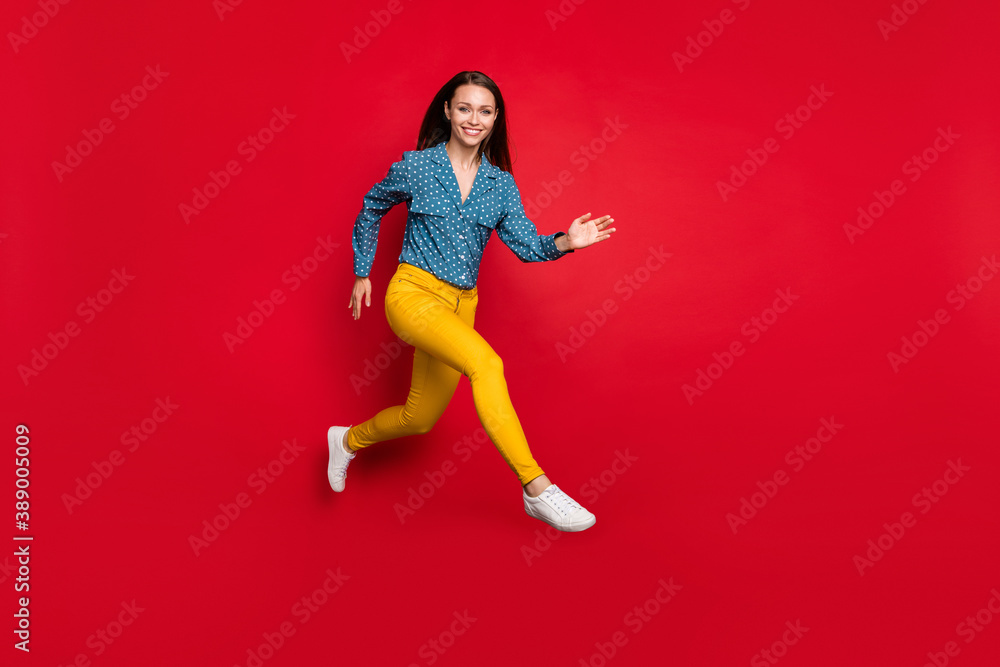 Full length body size view of attractive fit cheerful girl jumping running active motion isolated bright red color background Full length body size view of attractive fit cheerful girl jumping running active motion isolated bright red color background