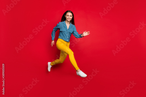 Full length body size view of attractive fit cheerful girl jumping running active motion isolated bright red color background