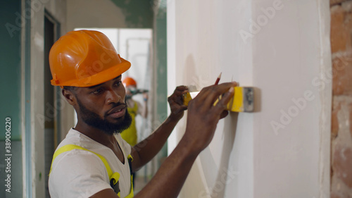 Canvas Print African male worker checking level of the wall with the bubble level tool