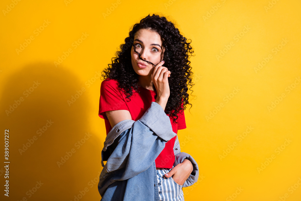 Photo of charming girl play curl hold mustachio pout lips wear red top striped jeans jacket isolated yellow color background Photo of charming girl play curl hold mustachio pout lips wear red top striped jeans jacket isolated yellow color background