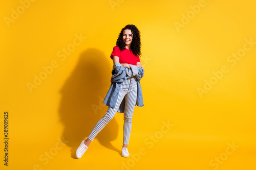 Full length photo of charming girl crossed hands wear striped jeans red t-shirt jacket sneakers isolated yellow color background