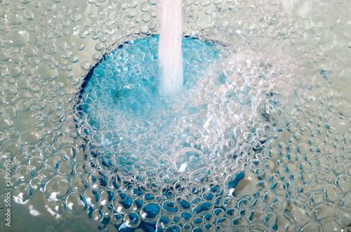 Slika na platnu Overflowing water in a blue glass, full overflow glass with water and bubbles