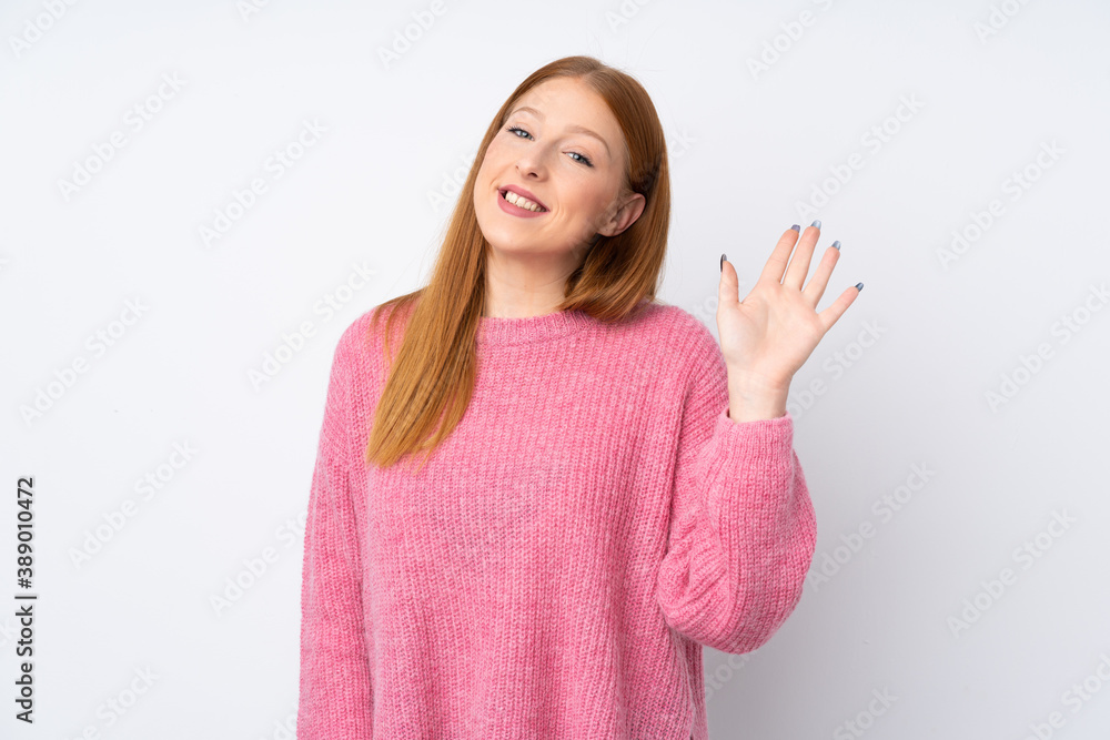 Young redhead woman with pink sweater over isolated white background saluting with hand with happy expression Young redhead woman with pink sweater over isolated white background saluting with hand with happy expression