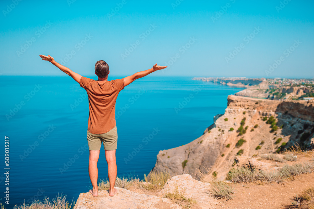 Tourist man outdoor on edge of cliff seashore Tourist man outdoor on edge of cliff seashore