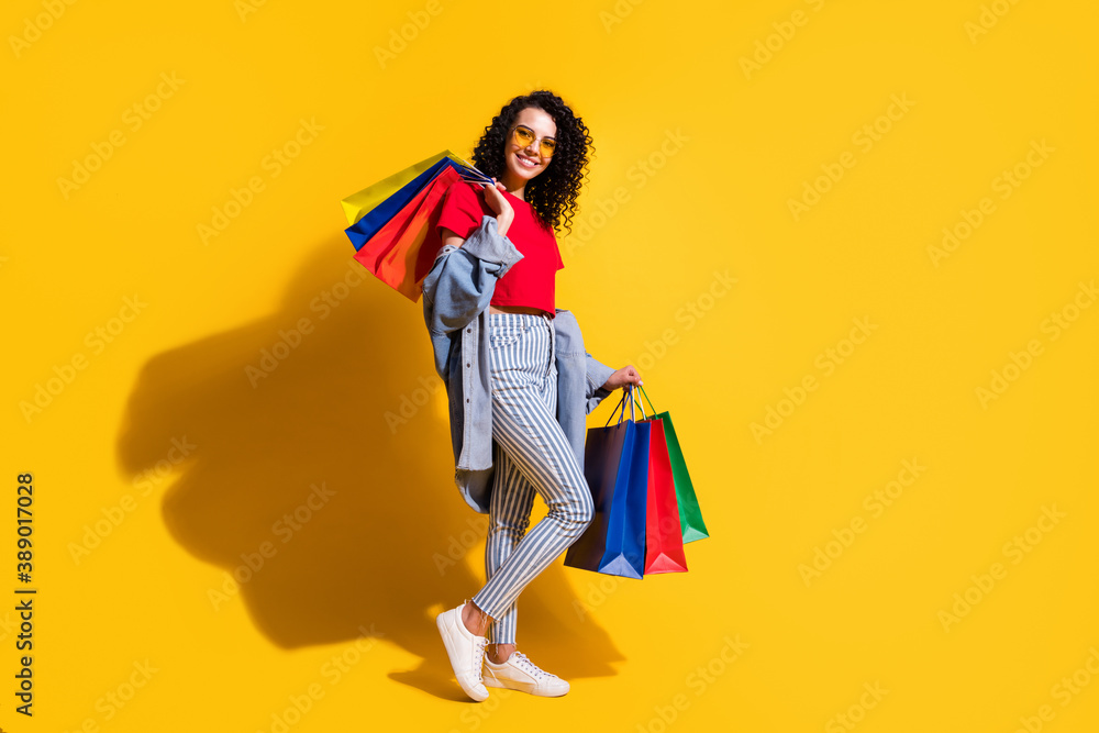 Profile photo of lady look camera hold shop packets wear red t-shirt striped jeans jacket sunglass sneakers isolated yellow color background