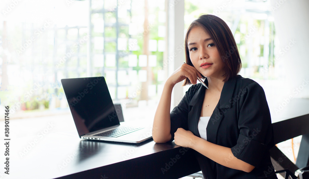 Asian business women use computers at their desks and work. Smile and look at the camera Asian business women use computers at their desks and work. Smile and look at the camera