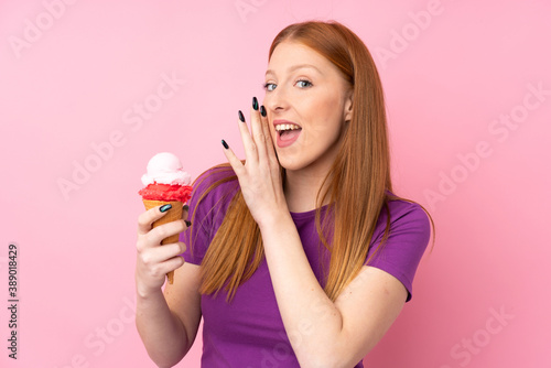 Young redhead woman with a cornet ice cream over isolated pink background whispering something