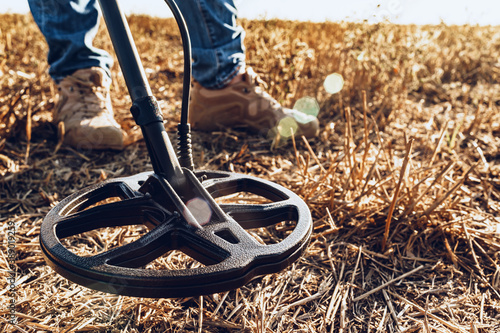 Fotografie Man with metal detector equipment searching for metal goods in the field