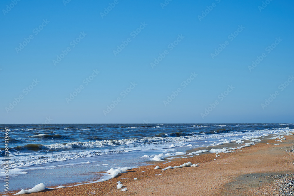 Image of sea foam on a sandy beach.