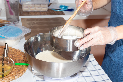 Using a sieve and a wooden spatula, the girl sifts the flour. Cooking process.