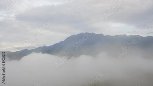 Time lapse MOUNT KINABALU foggy or the clouds while sunrise sky. Sea of clouds. Foggy valley mount ridge nature. Taken At RANAU, SABAH, BORNEO , MALAYSIA. time lapse motion pan right photo