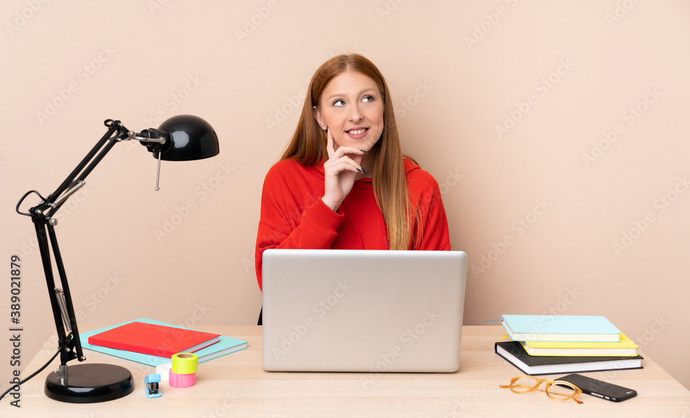 Young student woman in a workplace with a laptop thinking an idea while looking up Young student woman in a workplace with a laptop thinking an idea while looking up