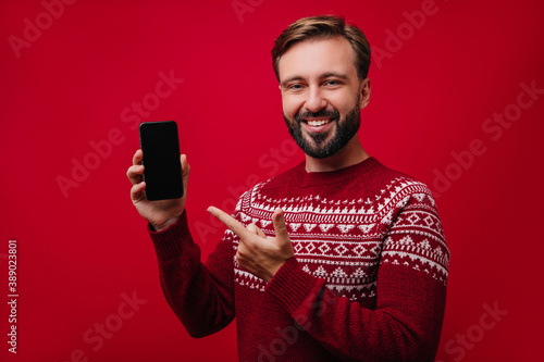 Cheerful caucasian man showing black smartphone. Dreamy european male model posing with phone. © Look!