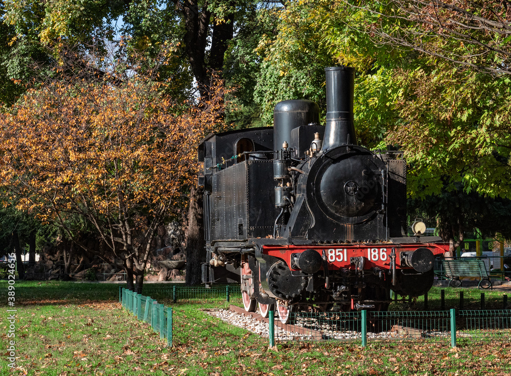 Fototapeta premium old black steam locomotive displayed in a public park on a sunny autumn day.Como,Italy