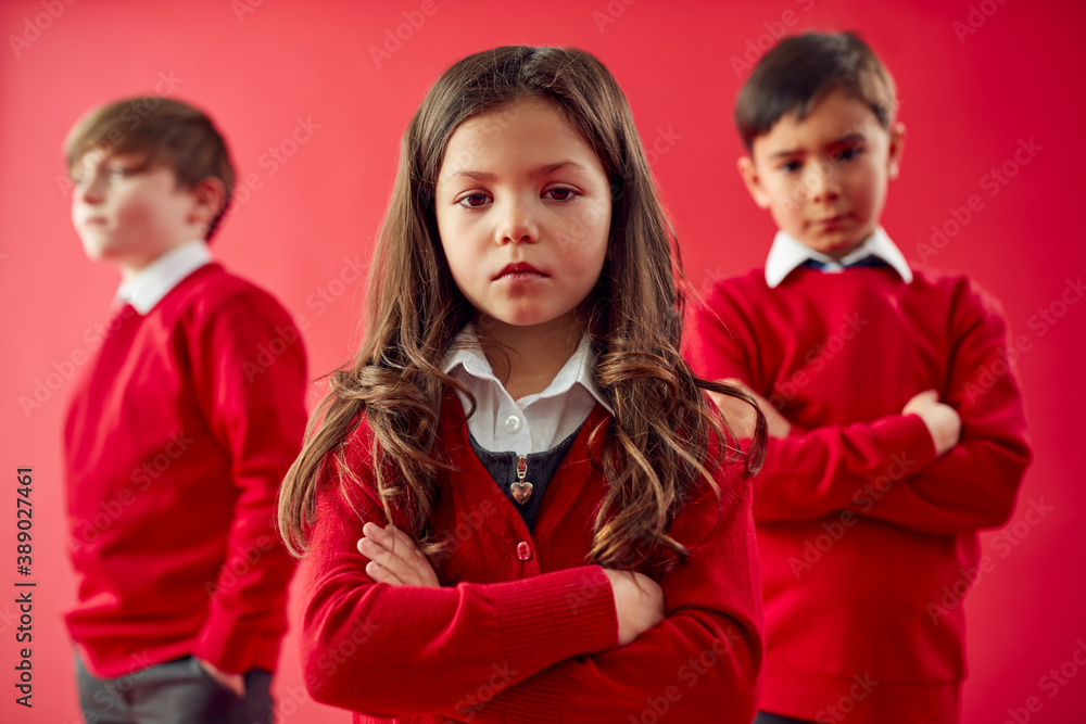 Group Of Elementary School Pupils Wearing Uniform Folding Arms Against Red Studio Background Group Of Elementary School Pupils Wearing Uniform Folding Arms Against Red Studio Background