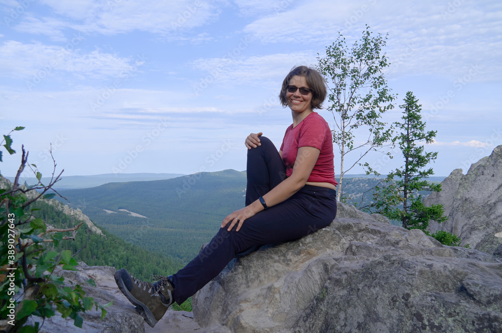 Smiling woman sitting on the top of rock