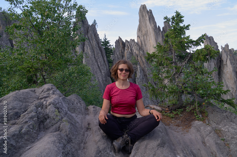 Naklejka premium Smiling woman sitting on the top of rock