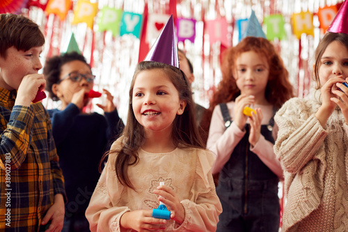 Group Of Children Celebrating At Birthday Party With Paper Hats And Party Blowers