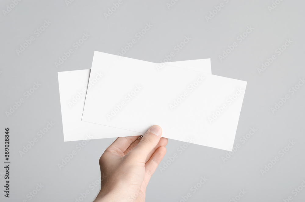 Fototapeta premium DL Flyer Mock-Up - Male hands holding blank flyers on a gray background.