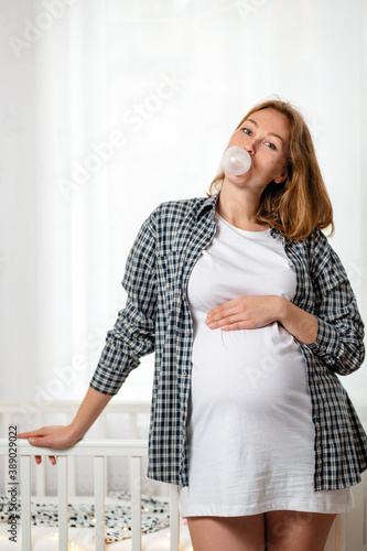 Canvastavla A young pregnant woman shows off her tummy and inflates a bubble of gum