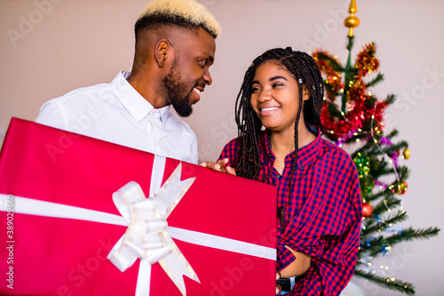 african american happy couple in love present a gift box in livingroom