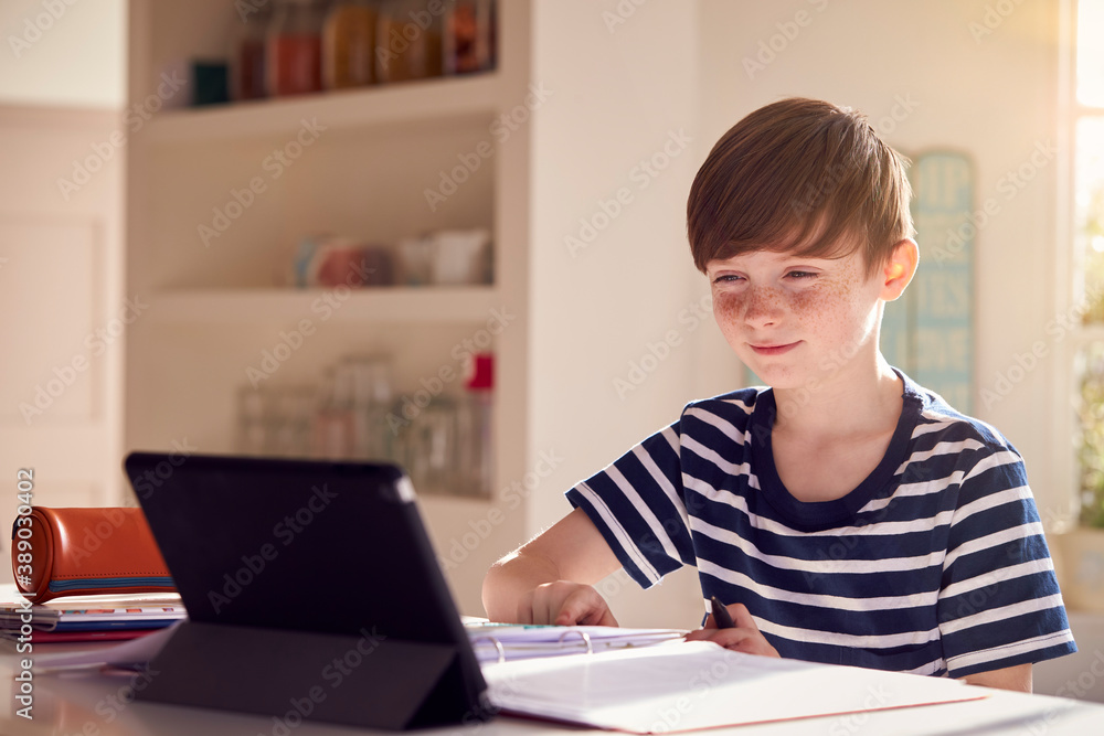 Boy Sitting At Kitchen Counter Doing Homework Using Digital Tablet Boy Sitting At Kitchen Counter Doing Homework Using Digital Tablet