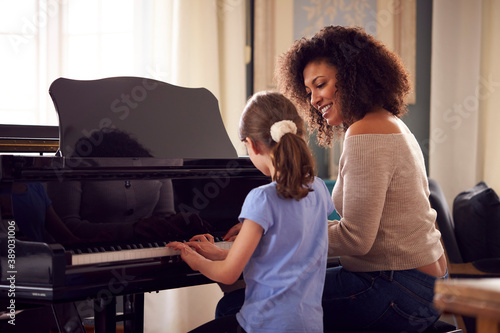 Canvas Print Young Girl Learning To Play Piano Having Lesson From Female Teacher