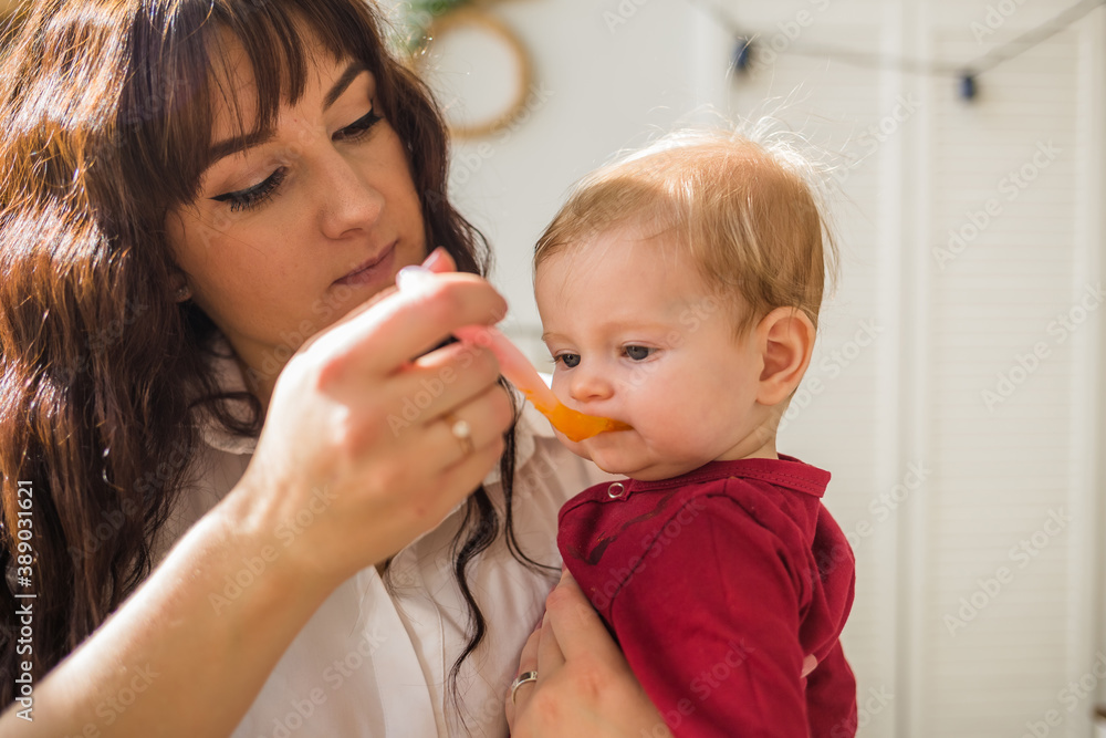 baby girl enjoys eating carrot puree from a spoon baby girl enjoys eating carrot puree from a spoon