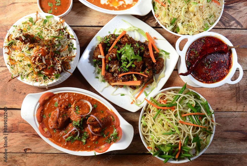 Assorted indian food chicken gravy,chicken biryani, pepper chicken, noodles, fried rice and dal tadka on wooden background. Dishes and appetizers of indian cuisine Assorted indian food chicken gravy,chicken biryani, pepper chicken, noodles, fried rice and dal tadka on wooden background. Dishes and appetizers of indian cuisine