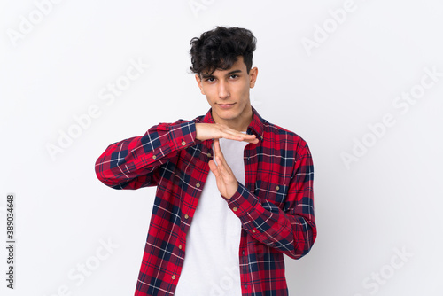 Young Argentinian man over isolated white background making time out gesture