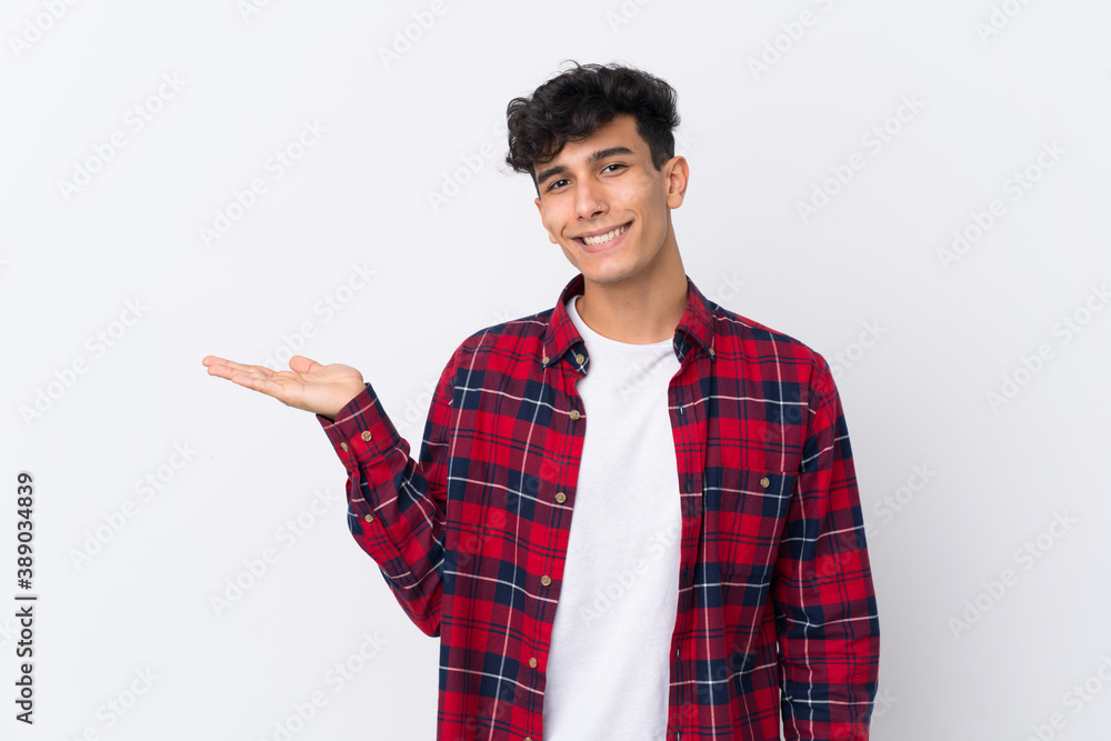 Young Argentinian man over isolated white background holding copyspace imaginary on the palm to insert an ad Young Argentinian man over isolated white background holding copyspace imaginary on the palm to insert an ad