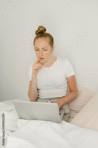 A red-haired girl with a computer in bed



