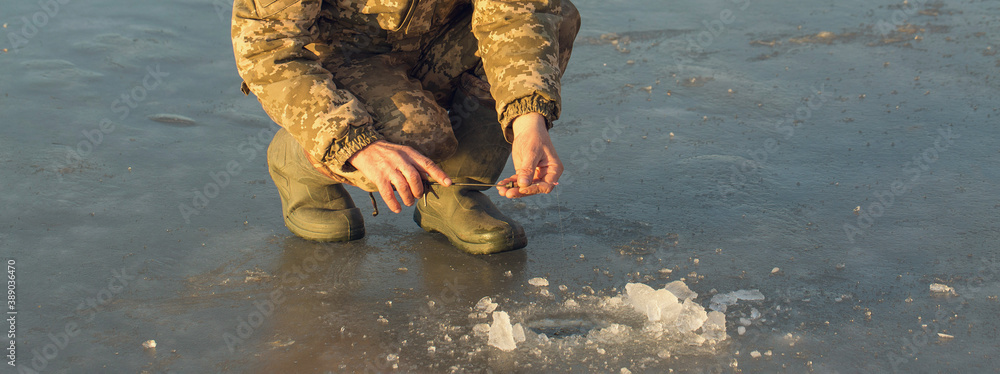 Φωτογραφία The guy on the winter fishing at the hole catches a small fishing pole