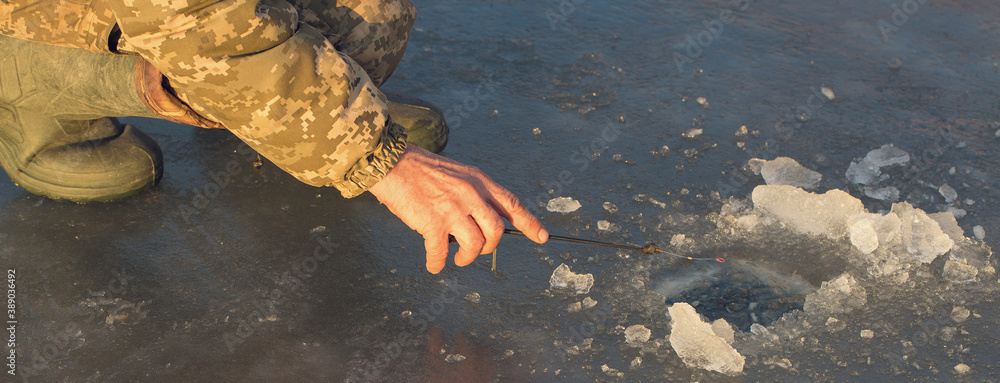 Φωτογραφία The guy on the winter fishing at the hole catches a small fishing pole