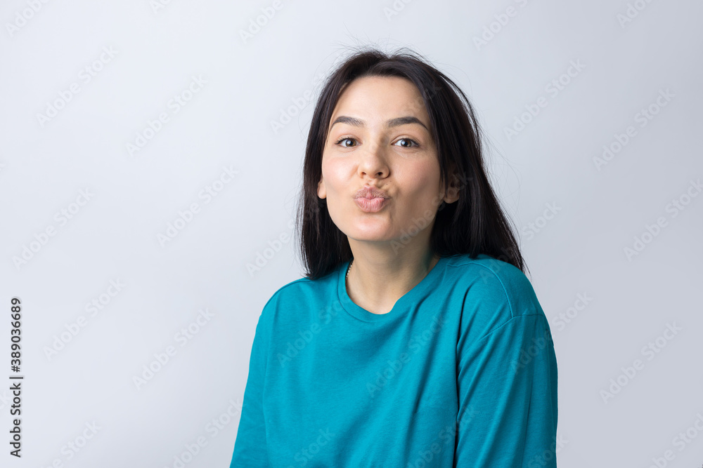 Portrait of flirting young woman blowing air kiss isolated over grey background Portrait of flirting young woman blowing air kiss isolated over grey background