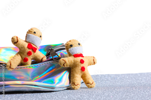 Gingerbread men in a protective mask are going out of neon holographic color bag on the bokeh white isolated silver background. The concept of art creative Christmas, Break lockdown