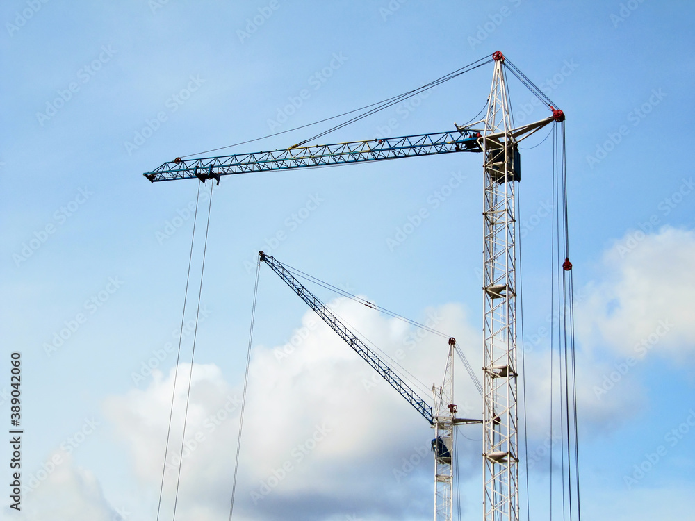 Two construction cranes against the sky