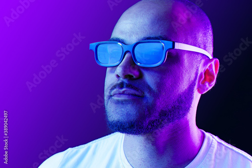 Positive black man in glasses posing in neon lights