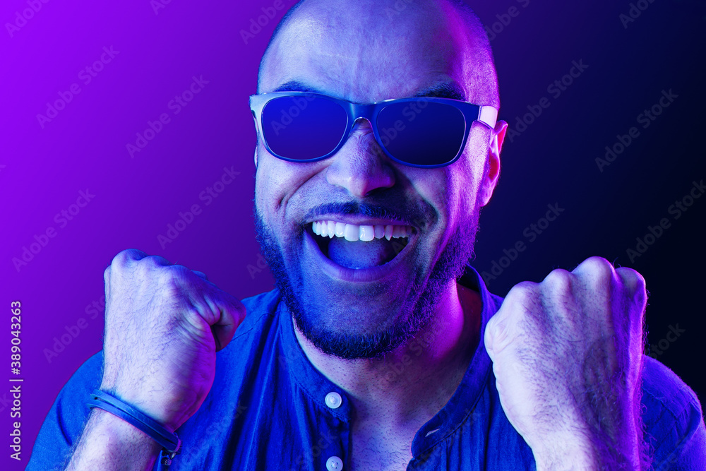Obraz premium Black man in glasses shouting with happiness in neon light
