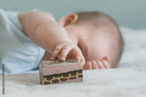 6 month old baby grasping vintage wooden block